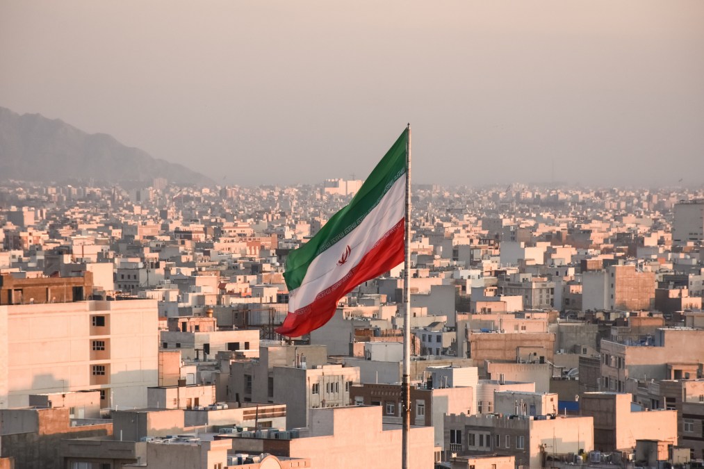 Iranian flag waving with cityscape on background in Tehran, Iran. (Sir Francis Canker Photography/Getty Images)