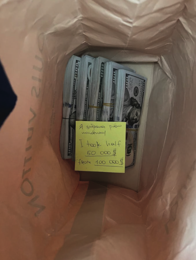 The second photo shows approximately half of the cash removed with a note affixed to the remaining cash written in Cyrillic and English. The English portion of the note reads: “I took half 50000$ from 100000$”
