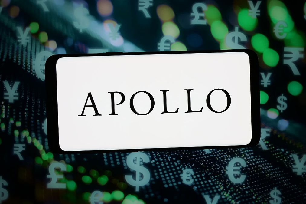 The logo of Apollo Global Management is displayed on a smartphone in front of abstract background. (Photo Illustration by Timon Schneider/Getty Images)